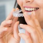 Woman placing a clear Invisalign-style aligner — orthodontics at The Dental Ethics, Pune
