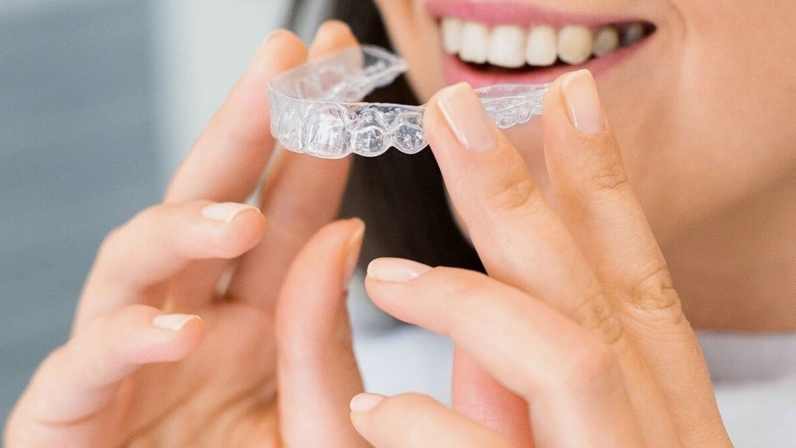 Woman placing a clear Invisalign-style aligner — orthodontics at The Dental Ethics, Pune